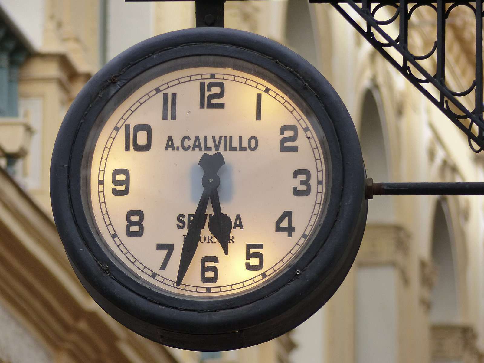 Reloj luminoso de la relojería A. Calvillo, Sevilla, colgado de un soporte de hierro en la calle Sierpes.